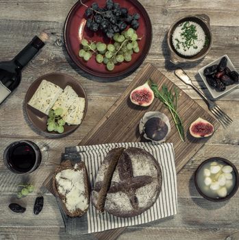 bread with cheeses and grapes and wineglass on wooden background