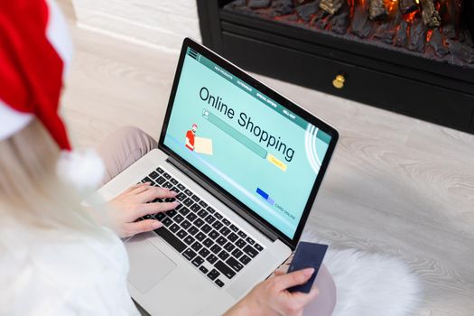 Christmas online shopping. Female buyer with laptop, copy space on screen. Woman buys presents, prepare to xmas eve, sitting among gifts boxes and packages. Winter holidays sales