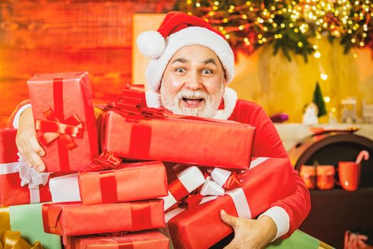 Excited senior Santa with Christmas gift. Christmas greeting card with Santa Claus. Grandfather with a white beard posing on the Christmas background