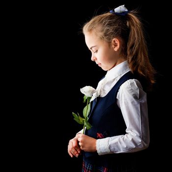 Beautiful little girl with a flower in her hand. The concept of style and fashion. On a black background.