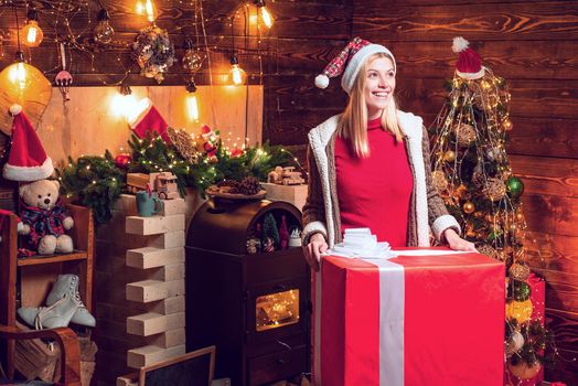 Woman received Christmas present gift box with surprise. Portrait of happy positive woman against wooden background in the decorated room