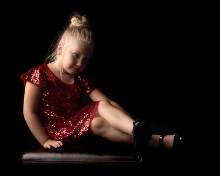 Beautiful little girl, studio portrait on a black background. The concept of a happy childhood, style and fashion.