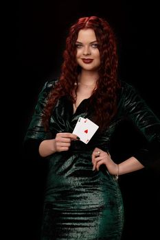 Redheaded woman whith a curly hair posing with a playing cards in her hands, on black background Win casino poker slots