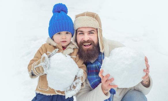 Winter, father and son play outdoor. Father and son making snowball on winter white background