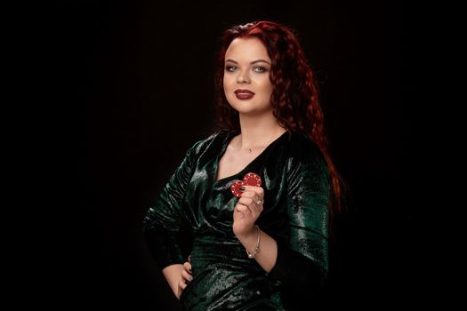 Awesome redheaded woman whith a curly hair and red lips, posing with chips in her hands, on black background Win casino holdem poker slots