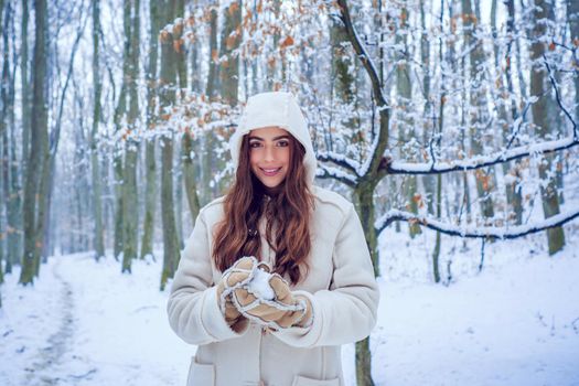 Winter woman fun. Girl playing with snow in park. Winter woman clothes. Winter woman snow