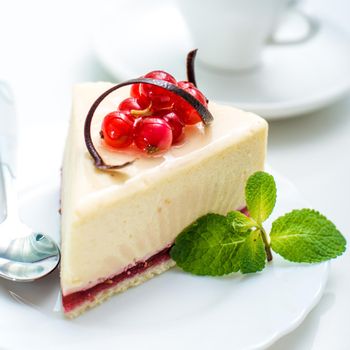 piece of cheesecake decorated with currant and spoon