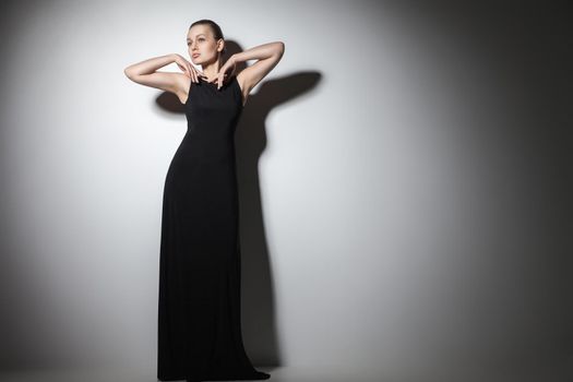 beautiful woman model posing in elegant black dress in the studio