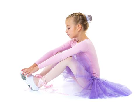 Cute little girl ballerina wears ballet shoes. The concept of learning to dance. Isolated on white background.