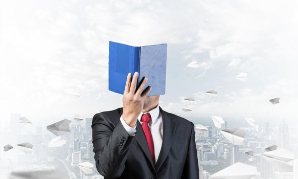 Businessman covered his face with paper organizer. Man in business suit standing on cityscape background with flying paper planes. Education and professional knowledges. Management and planning.