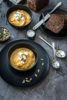 pumpkin soup in black plates on a gray concrete background