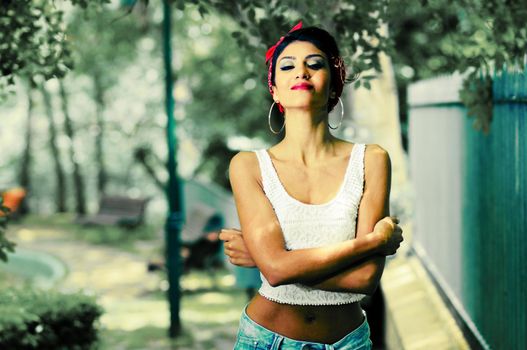 Portrait of a pin-up girl. American style, in a garden, wearing jeans and t-shirt