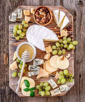 Cheese plate served with nuts and honey top view