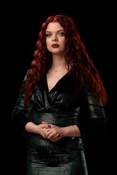 Young beautiful redhead woman with curly hair poses for the camera over black. Win casino poker slots