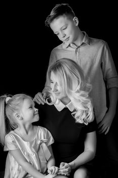 Happy young mother with her son and daughter in studio black and white photo. The concept of a happy family, upbringing.