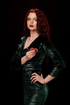 Gorgeous redheaded woman in a black dress turned sideways with chips in her hands, over black. Win casino holdem poker slots