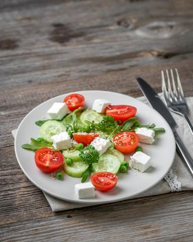 Appetizing greek salad with spices, cucumbers and feta cheese looking yummy, served with tableware