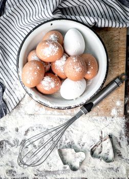 Eggs and whisk with two simple cooking forms, in process of baking, topview