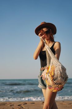 cheerful woman in a hat with sunglasses walking with a bag. High quality photo