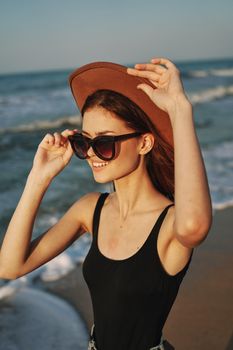 cheerful woman in sunglasses and a hat by the ocean walk summer. High quality photo