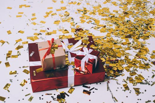 Christmas gifts, golden confetti, festive xmas presents wrapped in gift boxes with white and red ribbon, holiday design. High quality photo
