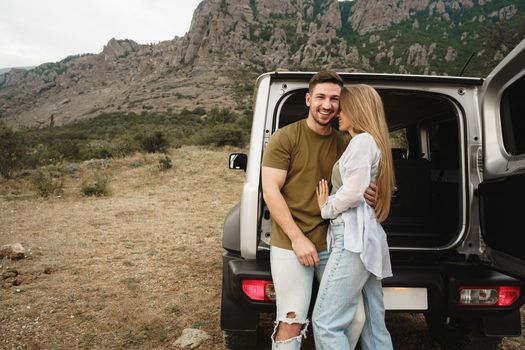 Young happy couple on a road trip sitting in car trunk outdoor