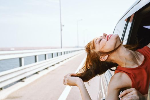 cheerful woman peeking out of the car window trip road travel. High quality photo