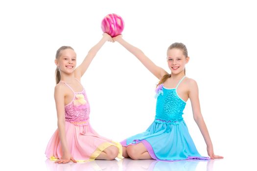 Two cheerful little girls gymnasts in competitions, perform exercises with the ball. The concept of children's sports, fitness, healthy lifestyle. Isolated on white background.