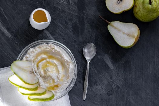 cottage cheese poured with syrup with slices of fresh pear, dark background, top view