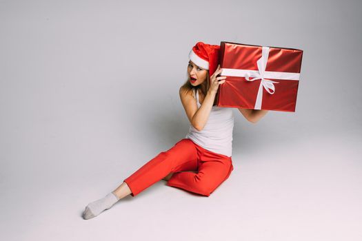 cheerful caucasian woman with red and white hat interests what is inside her gift