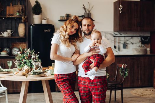 Happy young man and woman in pajamas while holding baby on Christmas eve. Holiday concept