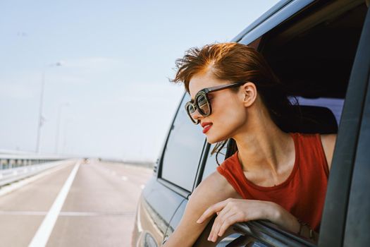 a woman is driving in a car on the road and looking out of the window. High quality photo