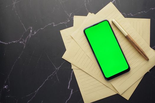 top view of smart phone and notepad on table .