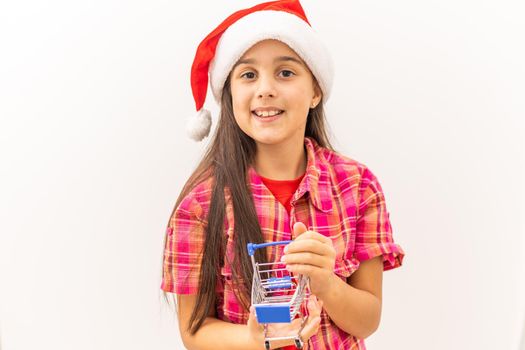 Full body little girl smiling and happy, holding a miniature shopping cart, concept of shopping, consumerism and christmas, can be used for internet purchases and commerce