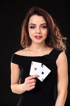 Young woman holding playing cards against a black background. Gambling. Poker. Two Aces.
