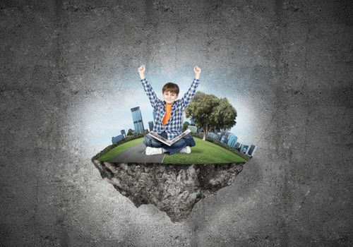 ECO concept floating island and happy kid boy with book sitting on it