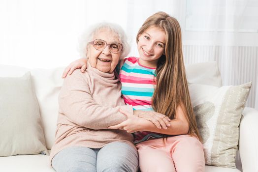 Smiling granddaughter sit hugging with grandmother