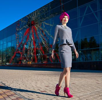Fashion photo of a beautiful woman in front of a building with reflection of Ferris wheel at summer time