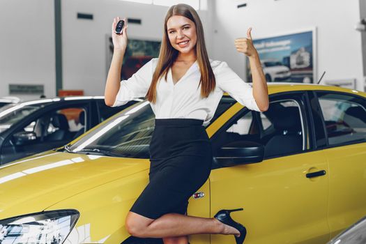 Young attractive woman buying a new car in car salon close up