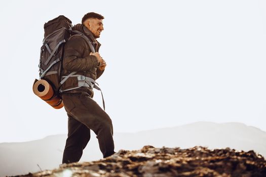 Male backpacker or hiker in hiking equipment standing at the top of the mountain