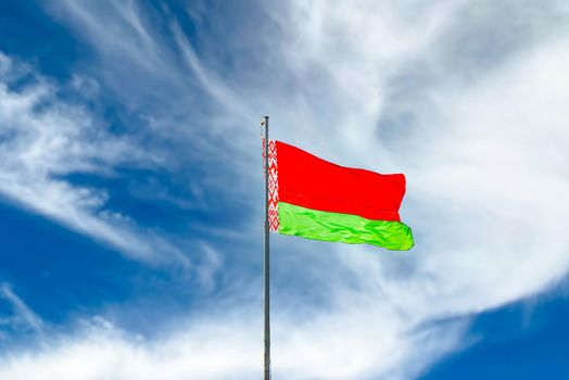 Flag of Belarus waving against blue sky with clouds