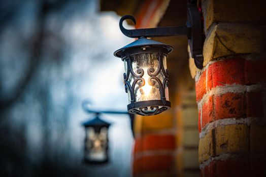 Old street lantern on stone building. Evening scene with lamp glow.