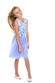 Portrait of a positive and stylish little girl in a summer dress, rejoices in the wind that blows and moves her dress and hair. The concept of beauty and fashion. Isolated on white background.