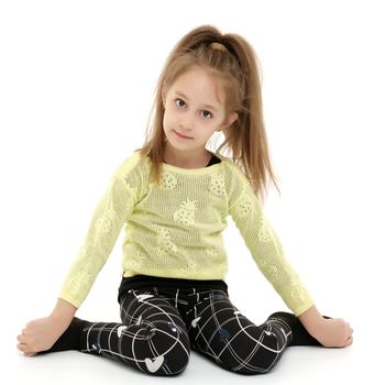 Beautiful little girl is sitting on the floor in the studio. The concept of a happy childhood, beauty and fashion. Isolated on white background.