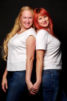 Young, beautiful women in white T-shirts are holding hands.