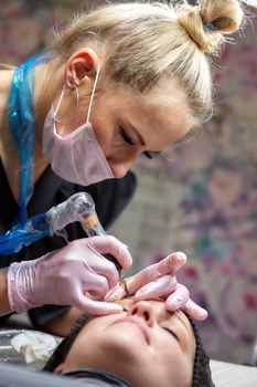 permanent makeup, eyebrow tattooing. The master makes permanent makeup using machine tattoos