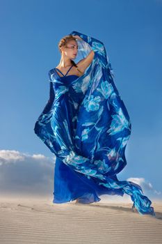 Portrait of a beauty woman in blue dress on the desert