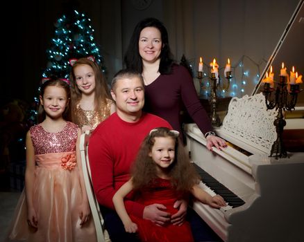 Happy young family with children at Christmas near a Christmas tree and a fireplace. The concept of holidays, winter, Christmas, Happy childhood, the harmonious development of children in the family.