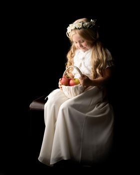 Little girl with a basket of apples. The concept of a healthy diet, happy childhood. On a black background.