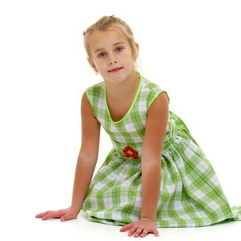 Beautiful little girl is sitting on the floor in the studio. The concept of a happy childhood, beauty and fashion. Isolated on white background.